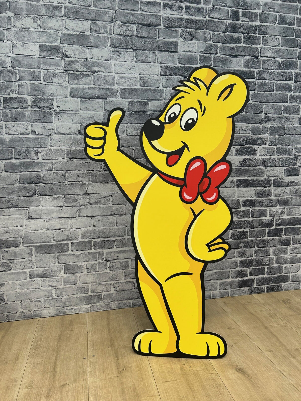 Goldbär-Figurenaufsteller vor einer Ziegelwand