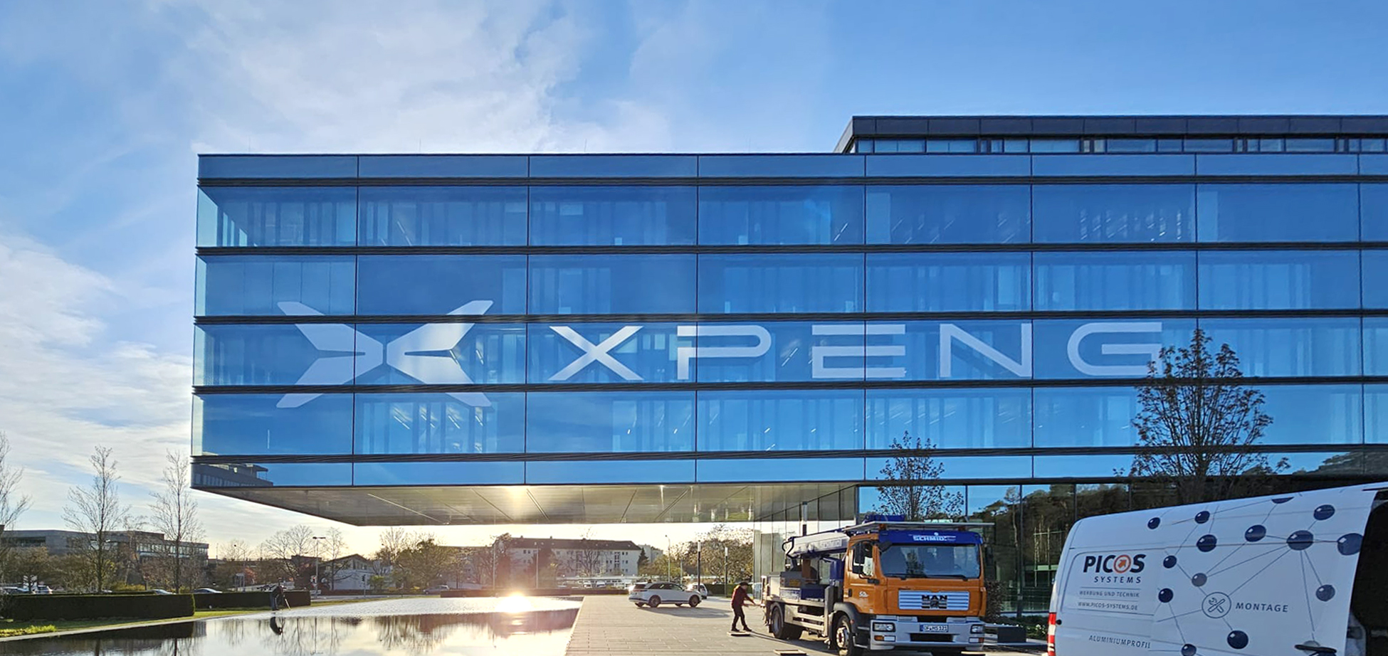 XPENG-Fassadenbeschriftung auf einer Glasfront mit PICOS-Montagefahrzeug